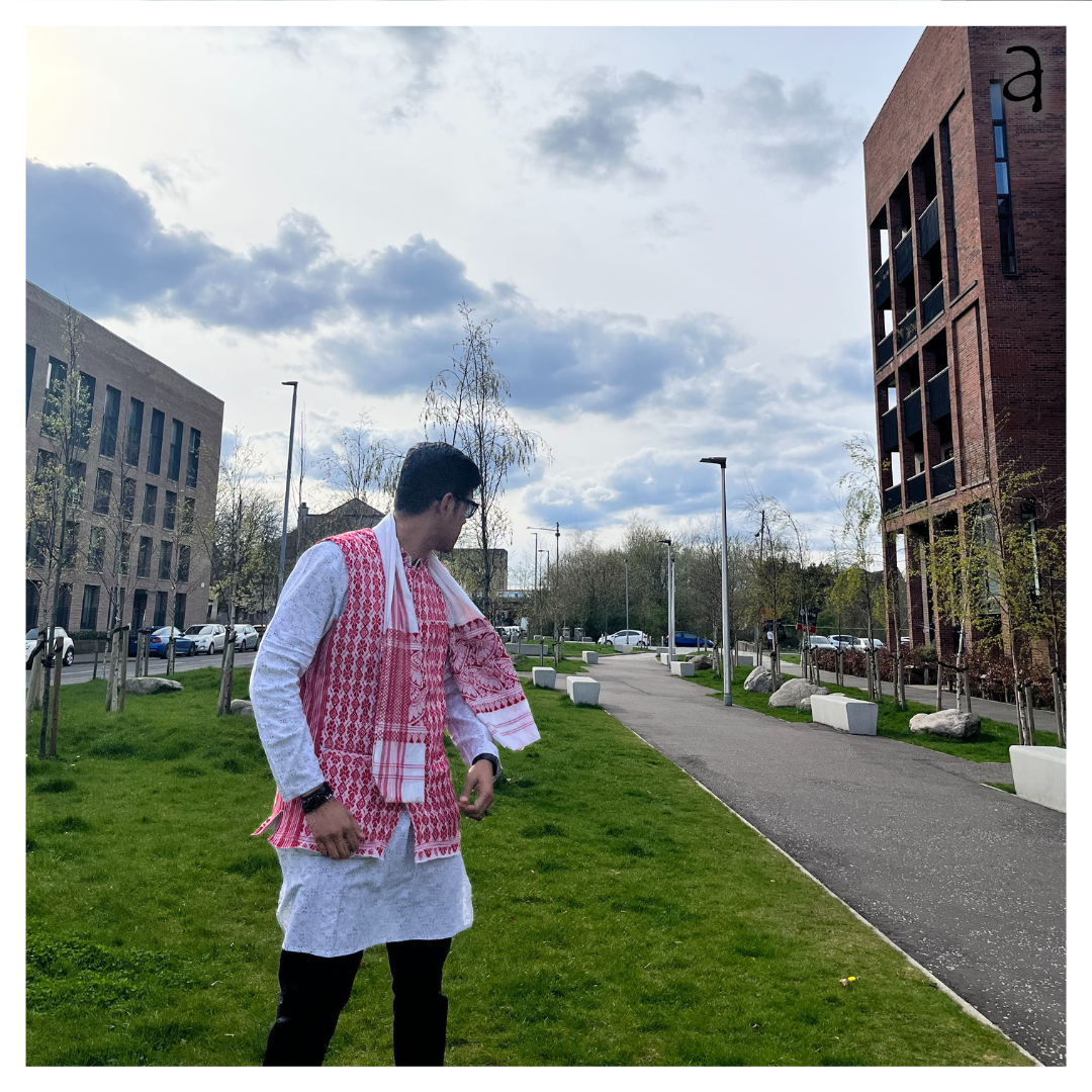 Person wearing a traditional outfit with a red vest in an urban setting with buildings and trees.